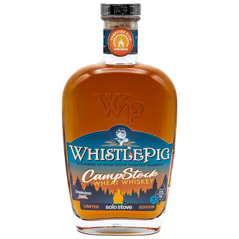 WhistlePig CampStock Wheat Whiskey bottle, an amber liquid-filled clear glass bottle featuring a prominent blue label with a pig mascot, "CampStock" and "Solo Stove" branding with a rustic forest silhouette and a blazing campfire icon, further distinguished by a Campfire Club Solo Stove medallion on its neck